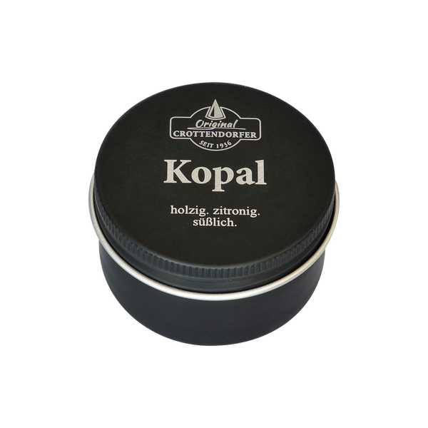 Eine schwarze Metalldose mit der Aufschrift „Kopal in der Schraubdeckeldose“ und den weißen Schriftzügen „holzig. zitronig. süßlich.“, hergestellt von Original Crottendorfer Räucherkerzen, ideal als Räucherkerzenbrenner, um die reinigenden Eigenschaften von Kopal zu genießen.