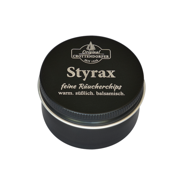 Eine schwarze Blechdose mit der Aufschrift „Styrax Räucherchips in der Schraubdeckeldose“ von Original Crottendorfer Räucherkerzen, auf deren Deckel „feine Räucherchips“ und „warm. süßlich. balsamisch.“ zu lesen sind, ideal für Räucherwerk, vor weißem Hintergrund.