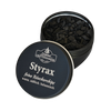 Eine runde schwarze Dose mit der Aufschrift „Styrax Räucherchips in der Schraubdeckeldose“ von Original Crottendorfer Räucherkerzen steht mit halb geöffnetem Deckel da, sodass man die schwarzen Chips im Inneren sehen kann. Der warme, süße, balsamische Duft ist perfekt für Fans von Räucherwerk.