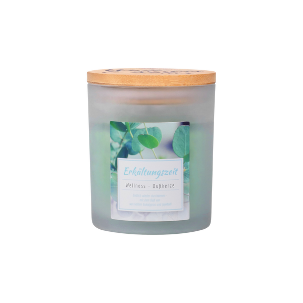 Die Wellness-Duftkerze Erkältungszeit von Candle Factory besteht aus einem Milchglas mit Holzdeckel und ist mit grünen Blättern beschriftet - eine natürlich duftende Wellnesskerze für die kalte Jahreszeit.