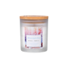 Die Wellnessduftkerze „Wintermärchen“ von The Candle Factory befindet sich in einem Milchglasgefäß mit Holzdeckel und zeigt schneebedeckte Bäume in Rosa- und Orangetönen. Sie wird aus Zutaten hergestellt, die durch nachhaltigen Anbau gewonnen werden.