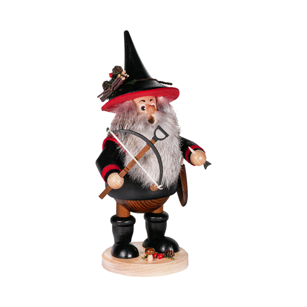 Der Räuberwichtel Armbrust schwarz/rot von DWU Drechselwerkstatt Uhlig ist eine hölzerne Räucherfigur eines bärtigen Mannes mit schwarzem Spitzhut und rotem Mantel mit Armbrust, die auf einem mit Pilzen und Eicheln verzierten Rundsockel steht.