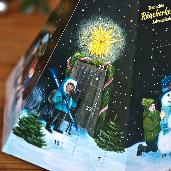 Pyramidenförmiger Räucherkerzen-Adventskalender – Pyramide mit einer Winterlandschaft, auf der eine Person mit Skiern zu sehen ist, einem Schneemann und 24 nummerierten Türchen.