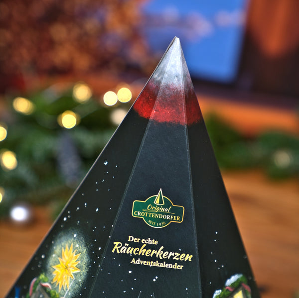 Ein Original-Räucherkerzen-Adventskalender von Crottendorfer – eine Pyramide in Form eines Berges mit schneebedecktem Gipfel und festlichem Sockel, gefüllt mit 24 verschiedenen Räucherkegeln.