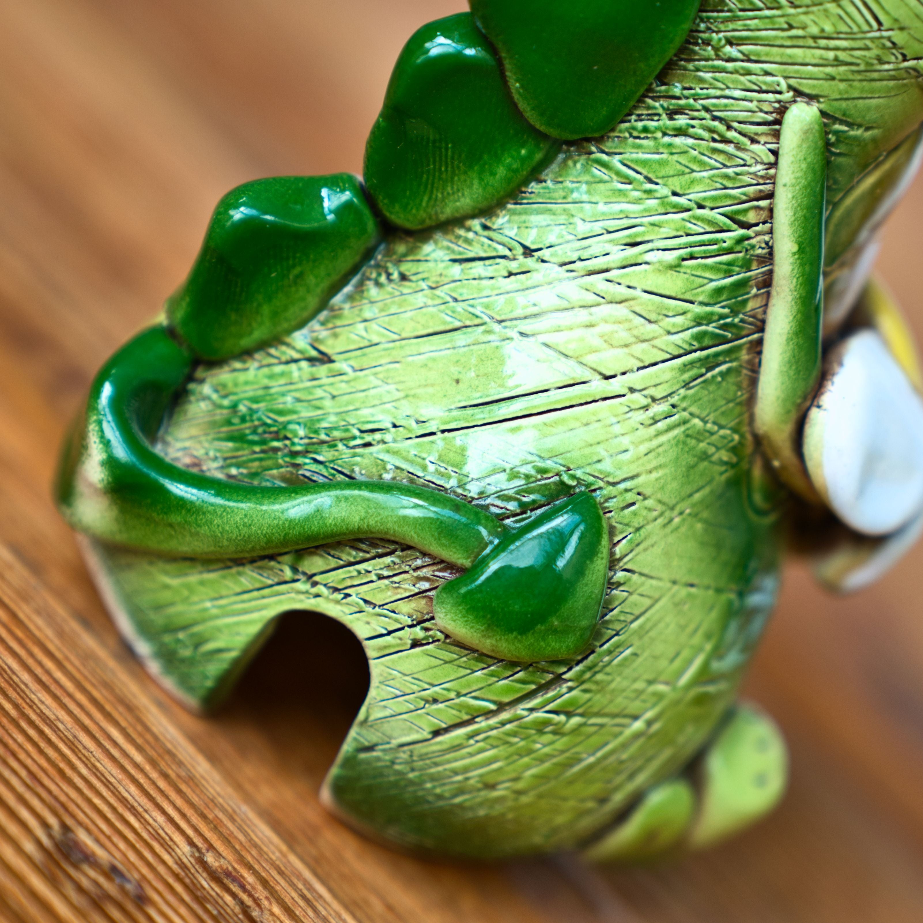 Nahaufnahme des KU Räucherdrache mit Blume von Kurilin DECO, die die detaillierten grünen Keramikschuppen und das Blumenmotiv auf dem unteren Rücken und Schwanz zeigt - perfekt, um eine Räucherkerze auf einer Holzoberfläche zu halten.