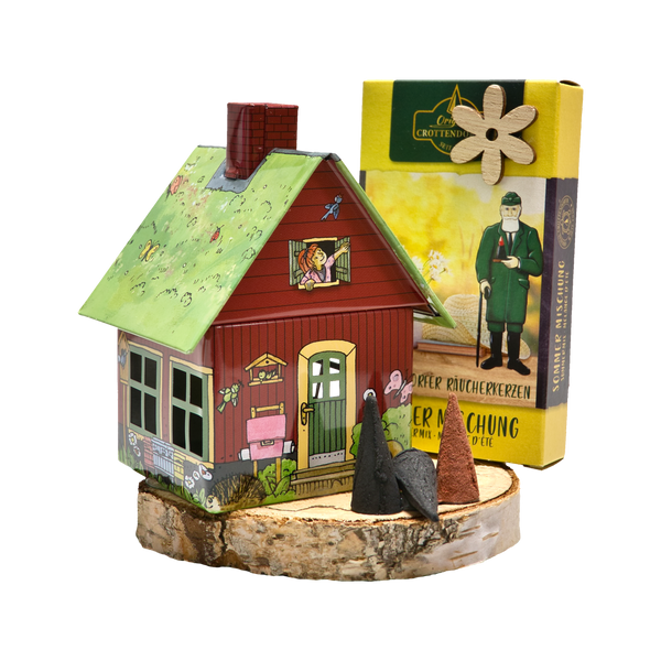 Ein Original Crottendorfer Räucherkerzen-Geschenkset enthält ein farbenfrohes Räucherhäuschen mit roter Außenseite und grünem Dach auf einem Holzsockel mit Abbildungen von Menschen und Tieren sowie eine gelbe Schachtel mit drei konischen Räucherkerzen.