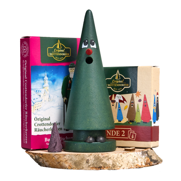 Das Geschenkset Tina Tanne mit Räucherkerzen und Memo-Spiel von Original Crottendorfer Räucherkerzen zeigt eine grüne, kegelförmige Räuchermaschine aus Holz auf einem Sockel, mit zwei Schachteln Räucherkegel und einem lila Kegel im Hintergrund.