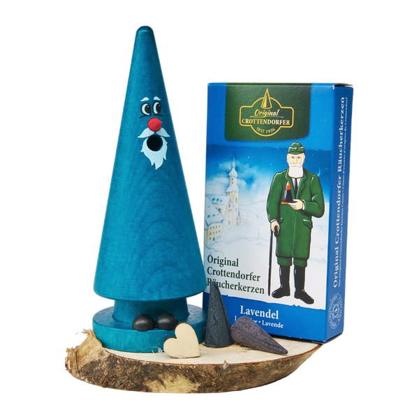 Das Geschenkset „Ziegenbein + Räucherkerzen“ von Original Crottendorfer Räucherkerzen besteht aus einer blauen Holzfigur mit Gesicht und Bart auf einem Sockel, die zusammen mit Herzformen und Räucherkegeln neben einer blauen Schachtel mit der Abbildung eines Mannes in Uniform präsentiert wird.