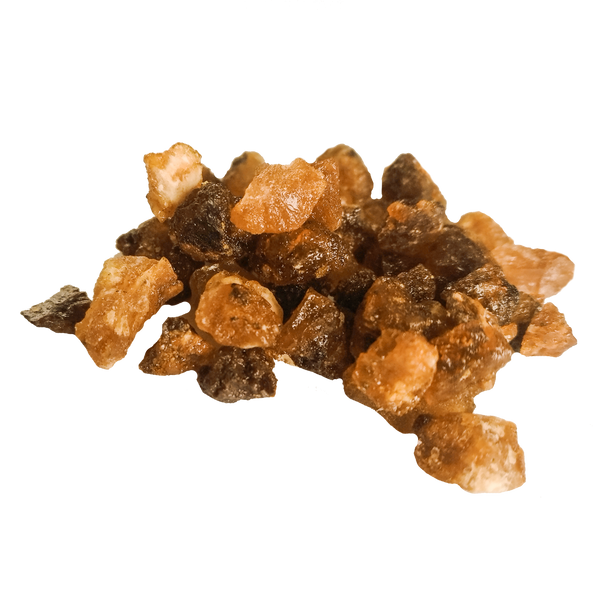 Ein kleiner Haufen bernsteinfarbenen Kristallzuckers, ähnlich dem Räucherharz Opoponax von Original Crottendorfer Räucherkerzen, ist auf einer glatten Fläche angeordnet.