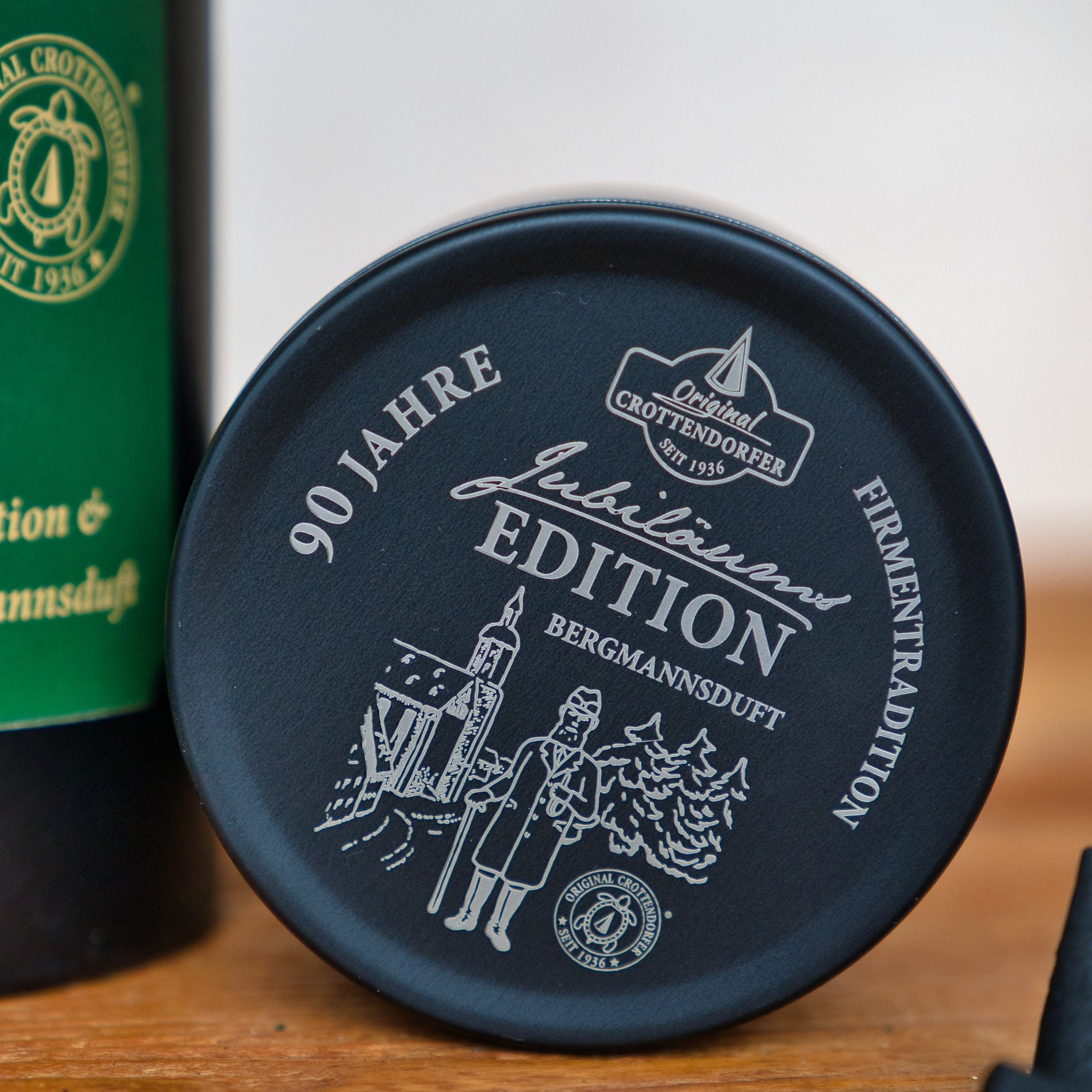 Die Jubiläums Räuchermann in der schwarzen Geschenkdose von Original Crottendorfer Räucherkerzen zeigt eine schwarze Dose mit Bergmanns-, Kirchen- und Baumkunst - zum Jubiläum 90 Jahre erzgebirgische Handwerkskunst. Perfekt für Sammler und Räucherkerzen-Fans.