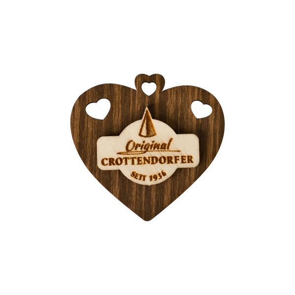Der Crottendorfer Magnet aus Holz von Original Crottendorfer ist ein hölzernes Herz mit zwei kleinen Herzausschnitten, dem Crottendorfer Logo und dem Schriftzug "Original CROTTENDORFER SEIT 1936" - perfekt für Ihren Kühlschrank.