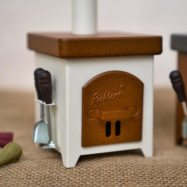 Ein kleiner, quadratischer, braun-weißer Hartmut Richter Räucherofen Hüttenofen mit seitlich hängenden Utensilien steht auf einer Jutefläche. Die Ofentür ist mit "Pickers" beschriftet.