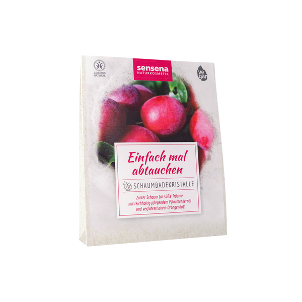 Eine Packung der Candle Factory Schaumbadekristalle "Einfach mal abtauchen" mit Pflaumenkernöl, die Pflaumen und deutschen Text auf weißem Hintergrund zeigt.