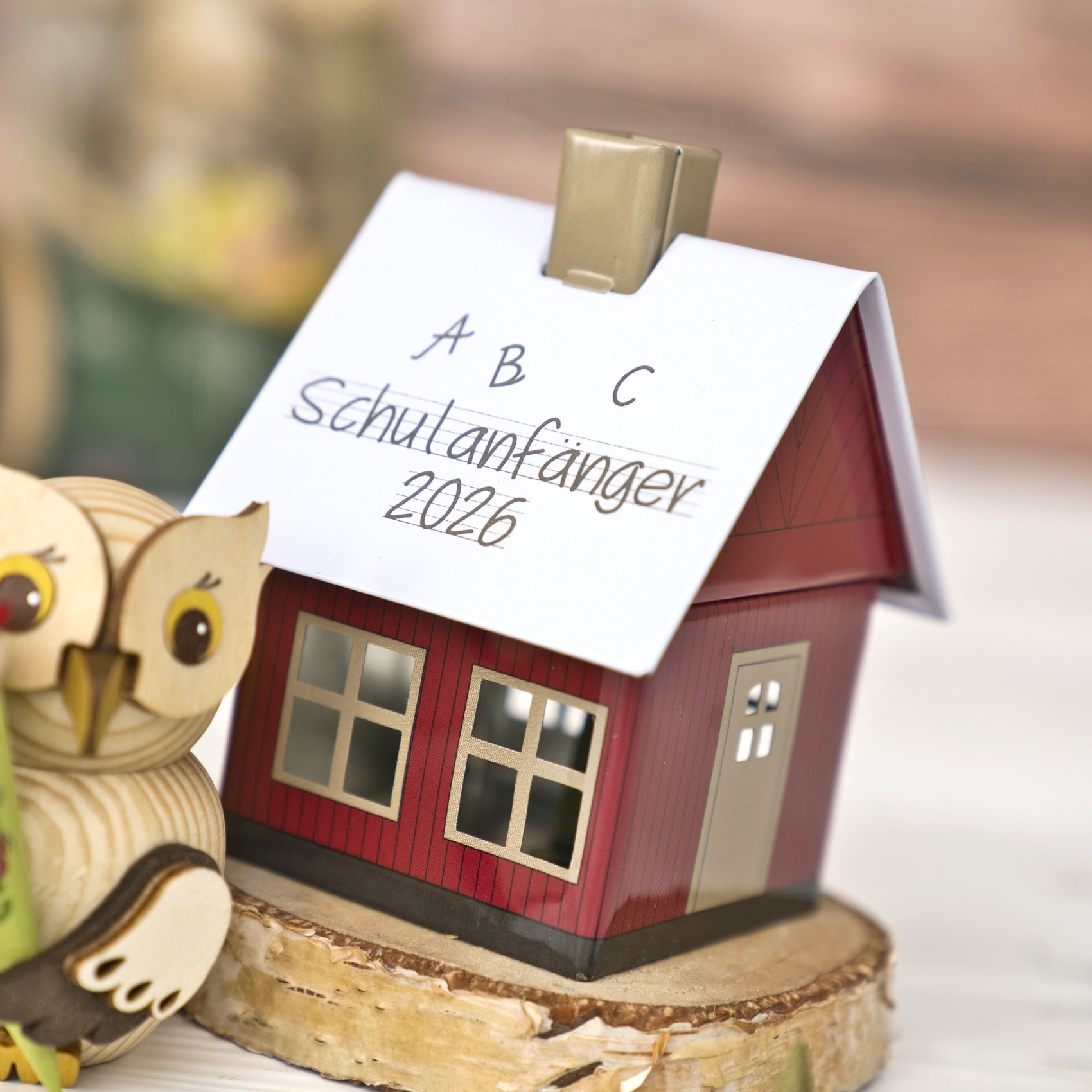 Das Original Crottendorfer Räucherhäuschen „Schulanfänger 2026“ ist ein kleines rotes Räucherhäuschen mit weißem Dach, das mit den Aufschriften „Schulanfänger 2026“ und „A B C“ versehen ist. Dazu gehört eine Eulendekoration aus Holz, die zusammen mit dem Räucherkerzenhalter auf einem Holzsockel steht – ein entzückender Räucherkerzenhalter, der sich perfekt zur Feier eines jeden Schulanfängers eignet.