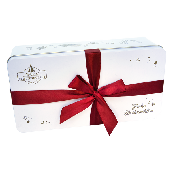 Das Stollen Geschenkset von Original Crottendorfer kommt in einer weißen, rechteckigen Geschenkbox mit goldenen Sternen, dem Schriftzug Frohe Weihnachten", einer großen roten Schleife und dem Markenlogo - ideal zum Verschenken von Crottendorfer Räucherkerzen.