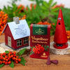 Eine Kiste Vugelbeer Raacherkerzln von Original Crottendorfer Räucherkerzen steht auf einem Holztisch, umgeben von erzgebirgischem Dekor: orangefarbene Beeren, ein rotes Hausornament und eine gemalte rote Zapfenfigur.