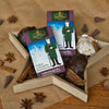 Zwei Schachteln „Original Crottendorfer Räucherkerzen Lebkuchengewürz“, auf deren Vorderseite ein Mann abgebildet ist, sind in einer sternförmigen Schale neben verschiedenen Lebkuchen, Zimtstangen und Sternanis auf einem braunen Untergrund ausgestellt und verströmen einen warmen Weihnachtsduft.