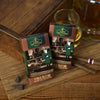 Zwei Schachteln mit Original Crottendorfer Räucherkerzen „Cuba Blend“ im Oldtimer-Design stehen neben einer Holzkiste auf einer Bambusmatte neben einem Glas Whisky, Zigarren und Schokoladenstückchen. Der dezente Räucherduft kubanischer Zigarren und vollmundiger Tabakblätter, den diese Räucherkerzen verströmen, rundet diese elegante Szene ab.