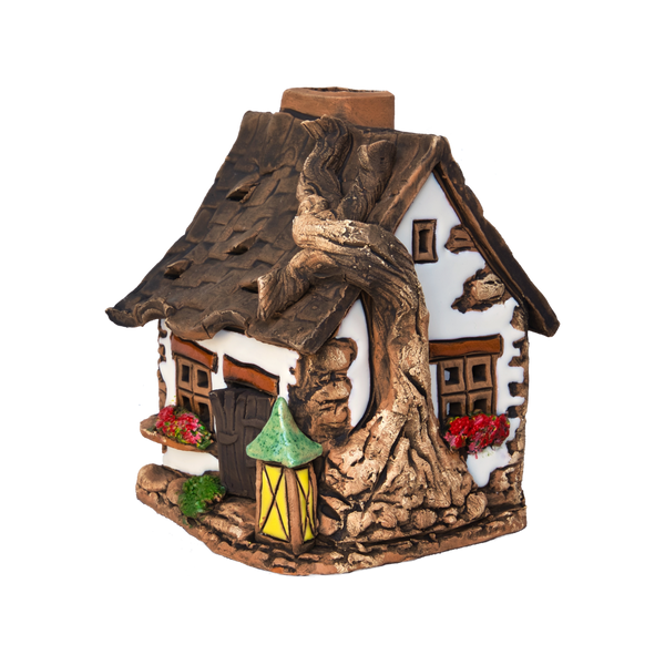Ein kleines, dekoratives Original-Crottendorfer-Räucherhaus aus Keramik mit „Wurzel auf Dach“-Motiv besticht durch ein braunes Dach, das an Baumwurzeln erinnert, Blumenkästen unter den Fenstern und eine gelbe Laterne neben der Haustür – alles vor einem weißen Hintergrund. Dieses bezaubernde Modell ist nur in begrenzter Stückzahl erhältlich.