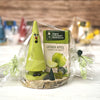 Eine grüne Holzfigur in Form eines Baumes mit Gesicht steht auf einem Holzsockel und ist in durchsichtige Plastikfolie eingewickelt. Daneben steht eine Schachtel mit der Aufschrift „Geschenkset Ziegenbein + Räucherkerzen“ von Original Crottendorfer Räucherkerzen – ein bezauberndes Geschenkset.