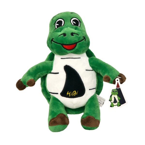 Das Kuscheltier „Hildi“ von Original Crottendorfer ist eine grüne Plüschschildkröte mit weißem Bauch und freundlichem Lächeln. Auf dem Arm ist ein Schild mit einem Bild von Hildi und „Hildi“ auf dem Bauch angebracht.