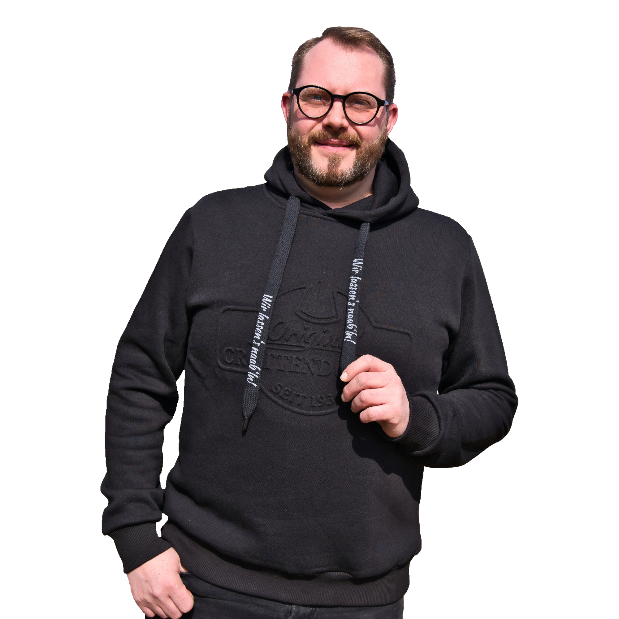 Vor rotem Hintergrund steht ein selbstbewusst lächelnder Mann, der einen Original Crottendorfer Kapuzenpullover mit Crottendorfer Räucherkerzen trägt und durch seine stylische Brille einen exklusiven Streetwear-Look besticht.