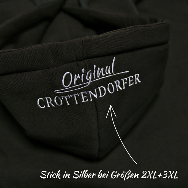 Nahaufnahme des Kapuzenpullovers „Crottendorfer Räucherkerzen“ von Original Crottendorfer in Schwarz mit weiß gesticktem „Original CROTTENDORFER“-Schriftzug. Silberner Stick für die Größen 2XL & 3XL; der Pfeil zeigt auf die klassische Stickerei im Streetwear-Stil.