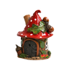 Eine verspielte Keramikfigur „Eichelhaus“ aus der limitierten Räucherhaus-Kollektion von Original Crottendorfer: ein winziges Häuschen mit einem roten, weiß gepunkteten Pilzdach, einer braunen Tür, einem grünen Blatt, Eicheln und Blumen – alles wunderschön präsentiert auf einem Messingteller vor einem strahlend weißen Hintergrund.