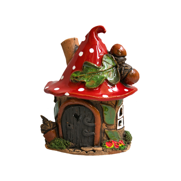 Eine verspielte Keramikfigur „Eichelhaus“ aus der limitierten Räucherhaus-Kollektion von Original Crottendorfer: ein winziges Häuschen mit einem roten, weiß gepunkteten Pilzdach, einer braunen Tür, einem grünen Blatt, Eicheln und Blumen – alles wunderschön präsentiert auf einem Messingteller vor einem strahlend weißen Hintergrund.