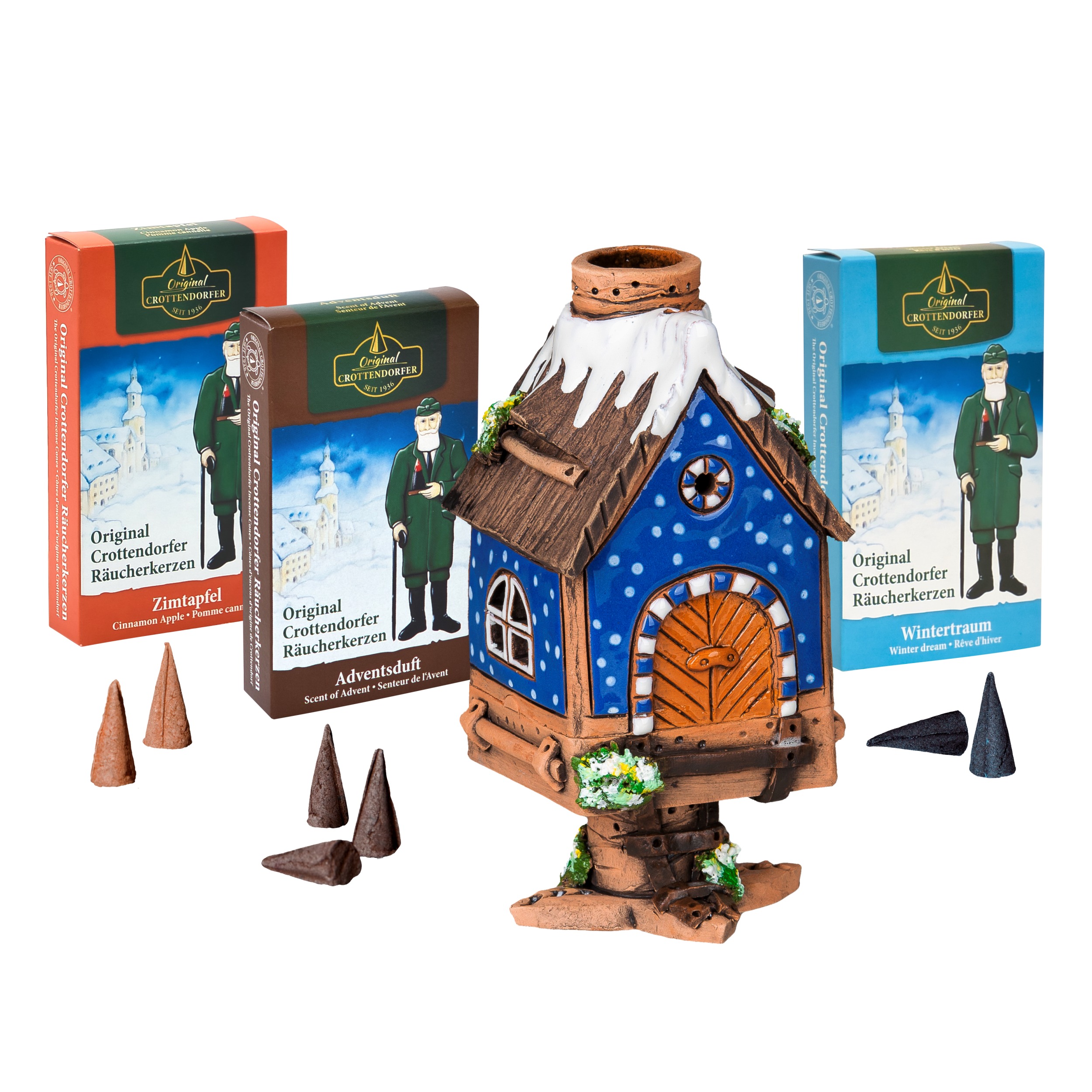 Das Original Crottendorfer Räucherhaus aus Keramik inkl. 3 Packungen Räucherkerzen besticht durch ein blaues Dach mit verschneiten Details und wird mit drei verschiedenen Räucherkerzenpackungen geliefert – ideal für festliche Weihnachtsdekoration vor weißem Hintergrund.