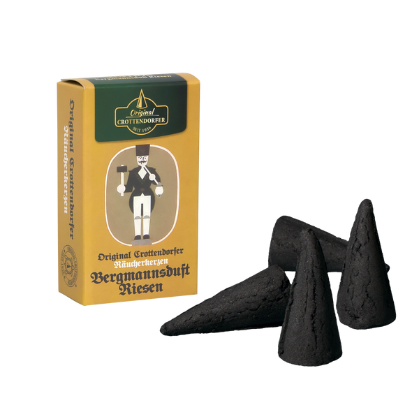 Eine Schachtel „Räucherkerzen Nostalgie Edition Bergmannsduft Riesen“ ziert eine Bergmannsillustration. Neben der Schachtel befinden sich drei schwarze, pyramidenförmige Räucherkegel, die einen Myrrhenduft verströmen, vor einem schwarzen Hintergrund, der das Produkt aufwertet.