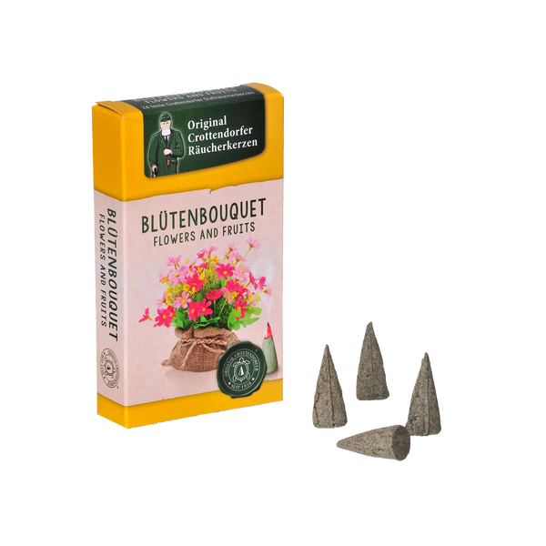 Eine gelb-rosa „Räucherkerzen Blütenbouquet“-Box von Original Crottendorfer Räucherkerzen mit Blumen auf der Vorderseite wird von vier grauen Räucherkegeln begleitet, die einen Hauch von Rosenblüten verströmen.