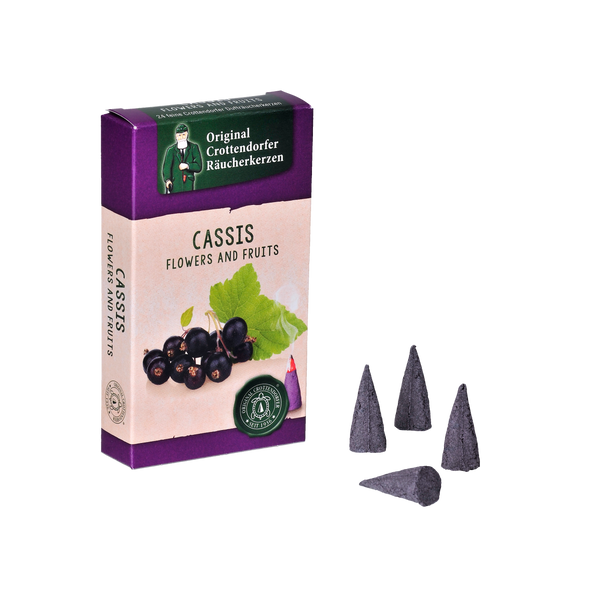 Die Räucherkerzen „Räucherkerzen Cassis“ von Original Crottendorfer Räucherkerzen in violetter Verpackung fangen die Essenz der Brombeere ein. In der Schachtel finden sich schwarze Johannisbeeren und Himbeeren mit grünen Blättern, begleitet von vier dunkelvioletten Kegeln.