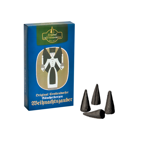 Eine Schachtel „Räucherkerzen Nostalgie Edition Weihnachtszauber“ von Original Crottendorfer Räucherkerzen zeigt Engelskunst mit Kerzen. Neben der Box sind vor schwarzem Hintergrund vier schwarze Zapfen zu sehen, die einen balsamisch-süßlichen Duft verströmen.