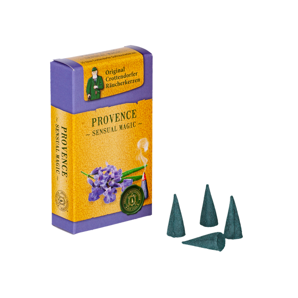 Eine Schachtel Original Crottendorfer Räucherkerzen Provence in lila und oranger Verpackung enthält lila Blüten und Gartennelke. Vier dunkelgrüne Räucherkegel liegen neben der Schachtel und verbreiten einen romantischen Duft, der jede Umgebung perfekt aufwertet.