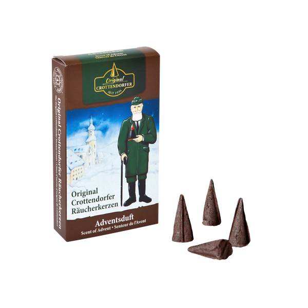 Die Original Crottendorfer Räucherkerzen Adventsduft-Dose zeigt eine Winterlandschaft mit Figur und vier braune Zapfen, die einen festlichen Duft verströmen. Sie trägt den Schriftzug „Adventsduft“ und verströmt in deutscher Sprache das warme Aroma weihnachtlicher Gewürze.