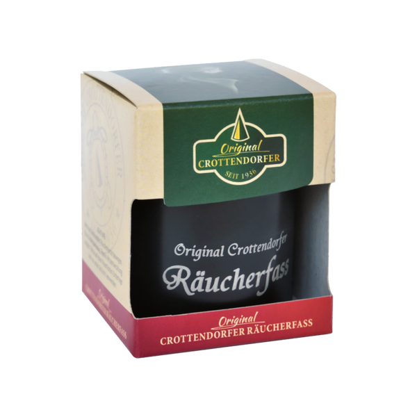 Die Verpackung des Crottendorfer Räucherfass zimt von Original Crottendorfer Räucherkerzen trägt ein grün-rotes Etikett mit der Aufschrift „Original Crottendorfer“ und „Seit 1936“. Durch den vorderen Ausschnitt kann man einen Blick auf die zeitlose Kunst des Räuchervergnügens werfen.