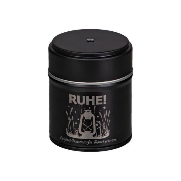 Das RUHE! Räucherfass von Original Crottendorfer Räucherkerzen ist eine schwarze Zylinderdose mit dem Schriftzug „RUHE!“ in Weiß, dekoriert mit einer Laterne und Gräsern, ideal für genussvolle Räuchererlebnisse.