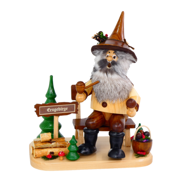 Der Waldwichtel Pilzsammler auf Bank von DWU Drechselwerkstatt Uhlig zeigt eine Holzfigur eines alten Mannes mit grauem Bart, Spitzhut und Pfeife auf einer Bank, mit Erzgebirgsschild, grünen Bäumen, Baumstämmen und einem Beerenkorb auf einem Holzsockel.
