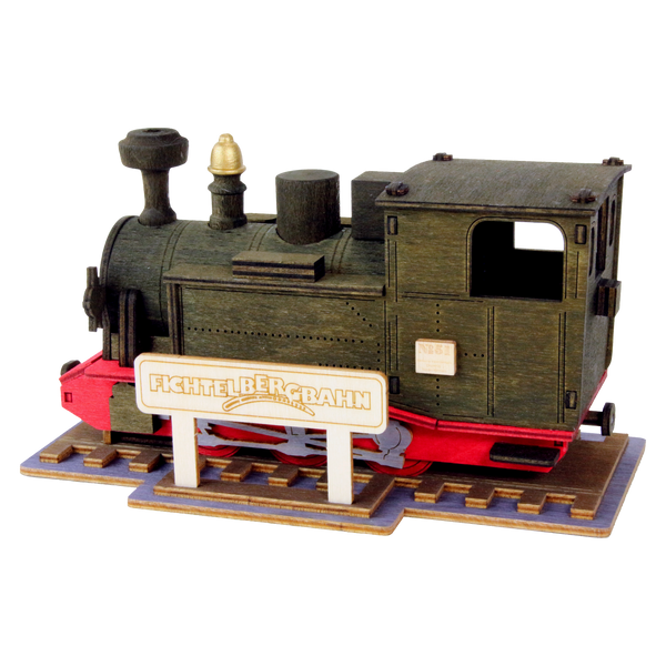 Bei diesem detaillierten Modell einer historischen Dampflokomotive von Lenk & Sohn handelt es sich um die Räucherlok Fichtelbergbahn. Sie verfügt über einen schwarzen Kasten und ein rotes Fahrgestell auf einem Holzständer mit der Aufschrift „Fichtelbergbahn“, wobei komplizierte Teile wie ein Schornstein und eine Kabine ihre Essenz einfangen.