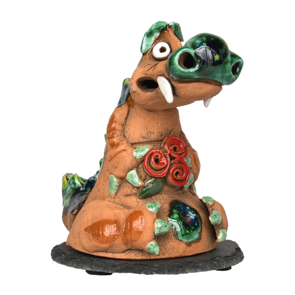Der Räucherdrache mit Schieferteller von Original Crottendorfer ist eine Keramikfigur eines skurrilen Dinosauriers mit farbenfrohen Akzenten wie grünen Stacheln und roten Rosen auf der Brust. Dieser einzigartige Keramik-Räucherdrache kombiniert Charme mit Funktionalität vor einem schlichten Hintergrund.