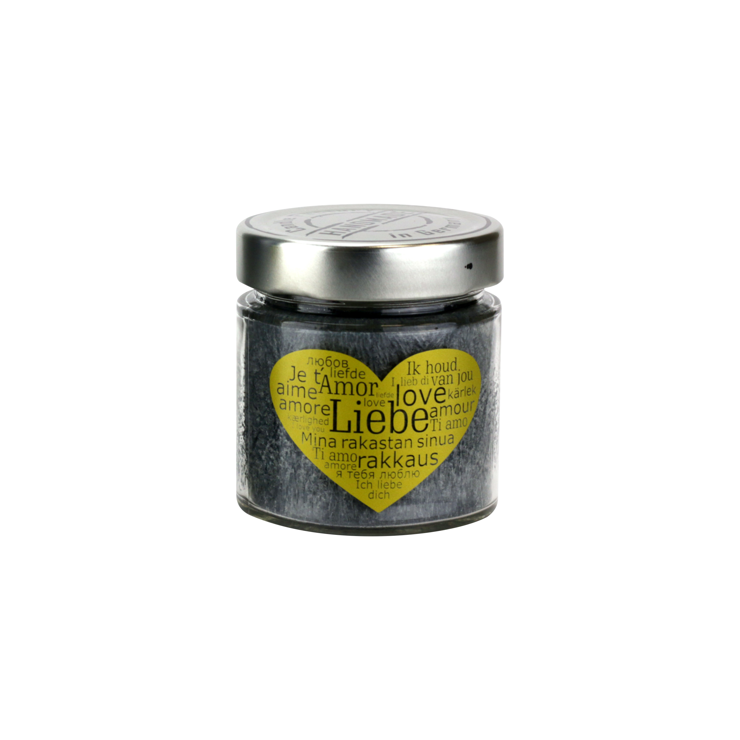 Die Duftkerze „Liebe“ von The Candle Factory in einem Glasgefäß mit Schraubverschluss verfügt über ein herzförmiges Etikett mit „Love“ auf Englisch, Französisch, Spanisch und Deutsch. Es ist auf einem schwarzen Hintergrund angebracht.