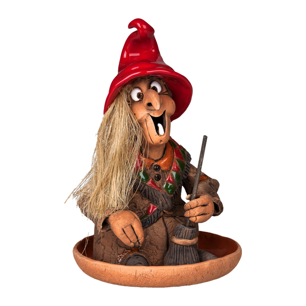 Die Original Crottendorfer Räucherhexe mit Keramikteller zeigt eine skurrile Hexenfigur mit rotem Hut, braunem Outfit, breitem Lächeln und strohartigem Haar, die einen Besen hält und auf einer Terrakottaschale vor schwarzem Hintergrund sitzt.